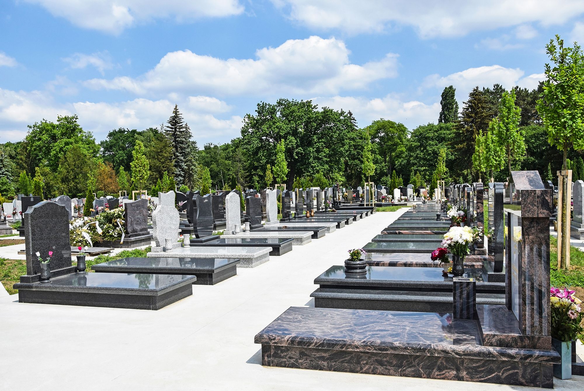 Ein friedlicher Friedhof mit Reihen polierter Steingräber unter strahlend blauem Himmel
